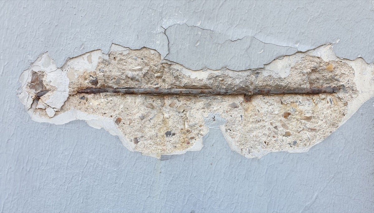 A close-up view of a noticeable crack running across a painted drywall surface, indicating damage.