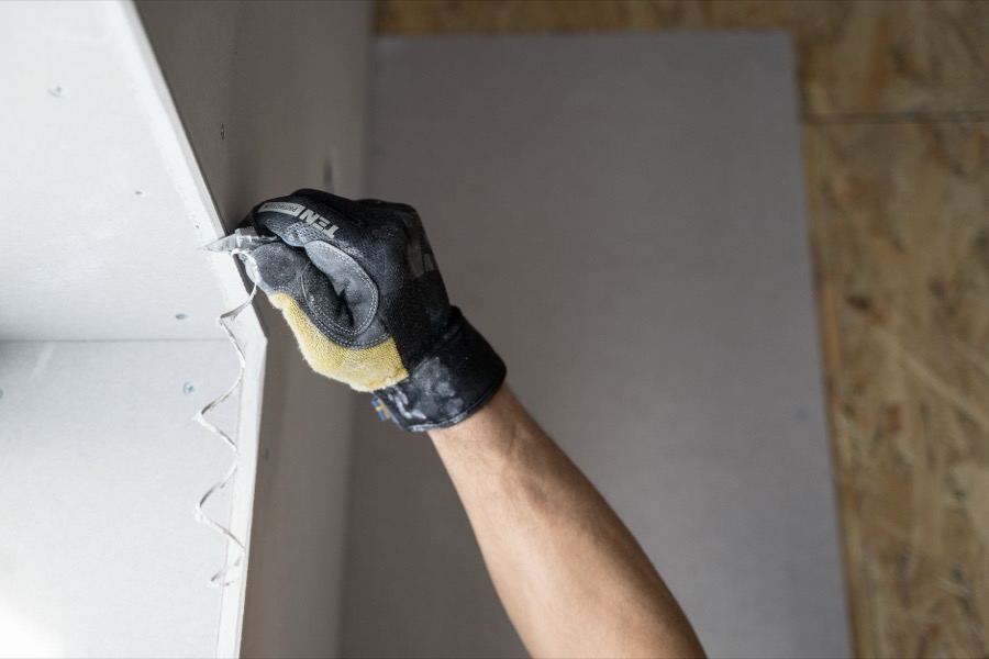 Assortment of drywall tools on a clean work surface, including taping knife, joint compound, and sandpaper.