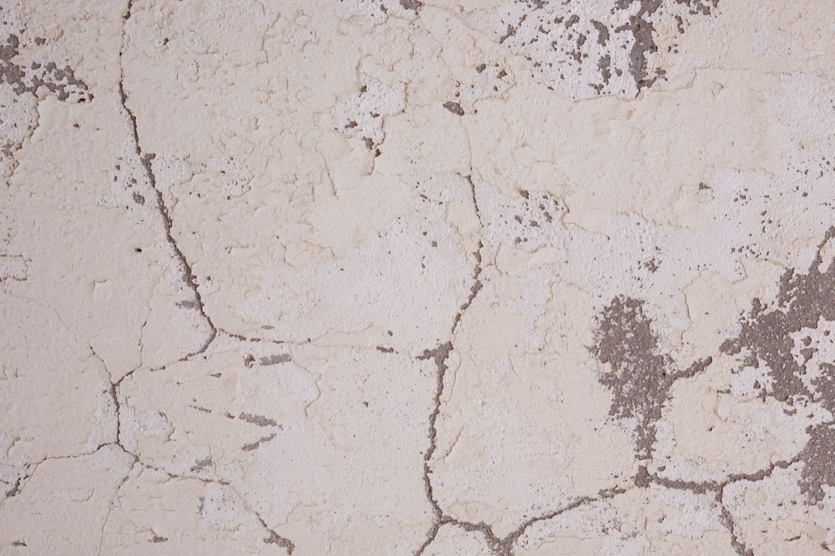 Close-up of a distinct crack in a white painted drywall ceiling, indicating structural or settling issues.