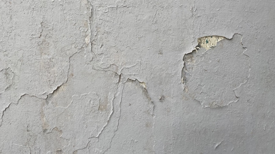 Hands applying joint compound to a repaired drywall crack, smoothing the surface