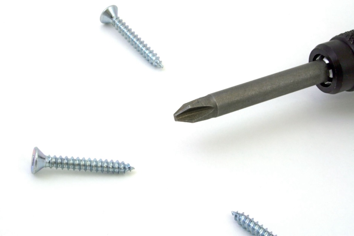 Close-up of a professional using a putty knife to apply spackle over a drywall screw pop.
