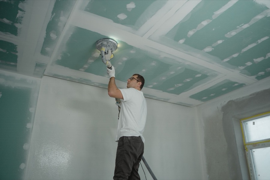 A collection of drywall repair tools, including spackle knives, joint compound, and sandpaper, laid out on a clean surface.