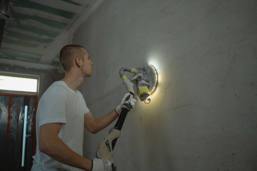 A close-up of a sanded and feathered joint compound patch on a drywall surface, ready for primer.
