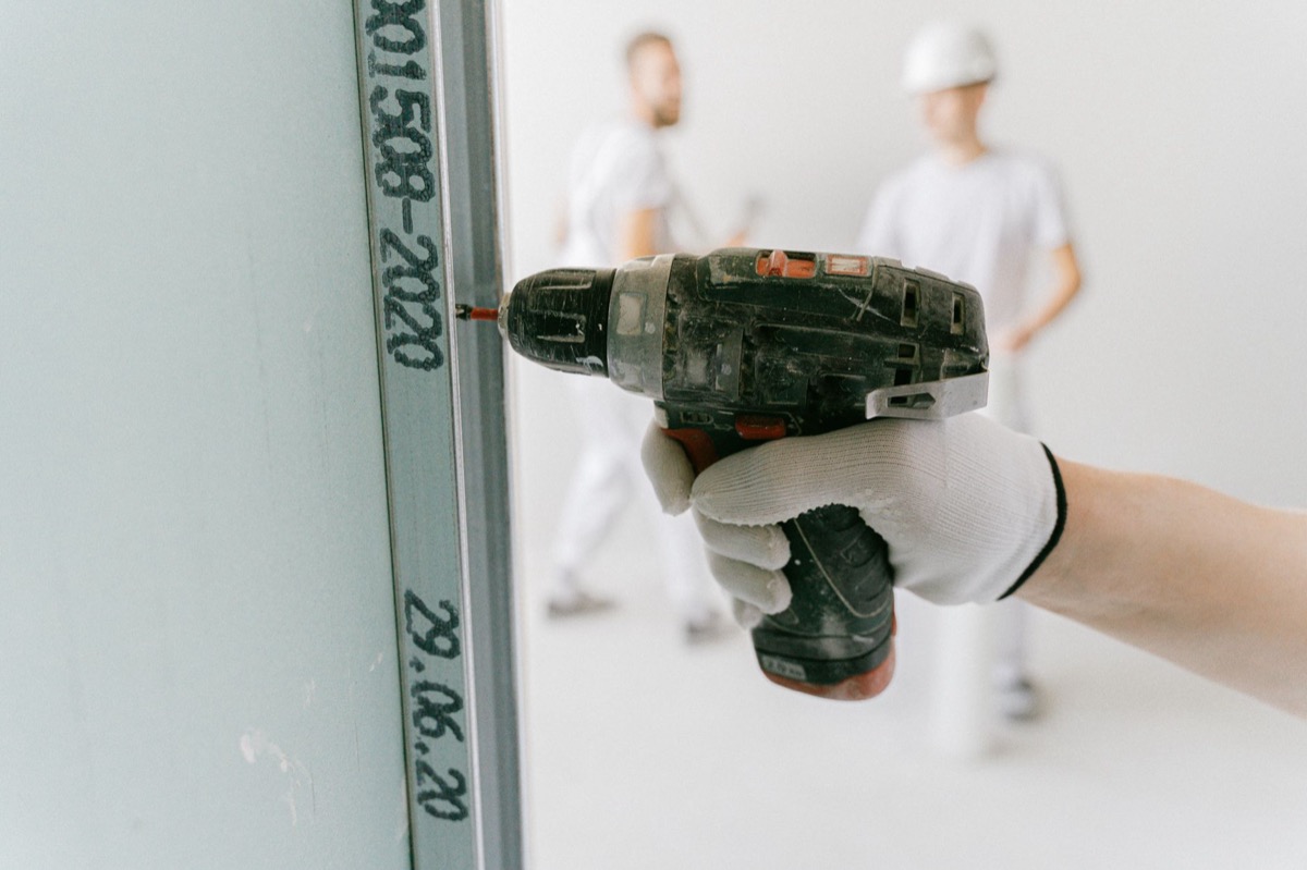 Close-up of a drywall surface with a visible 'nail pop' – a small bump where a screw or nail is pushing through, indicating a repair is needed.